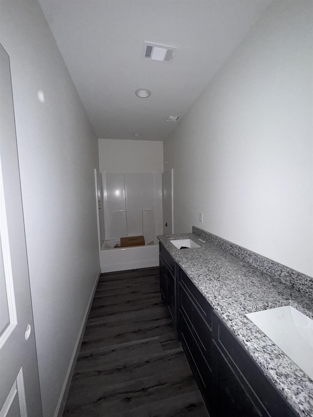 bathroom with double vanity, baseboards, visible vents, wood finished floors, and a sink