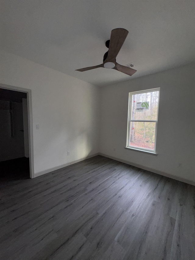 spare room featuring baseboards, ceiling fan, visible vents, and wood finished floors