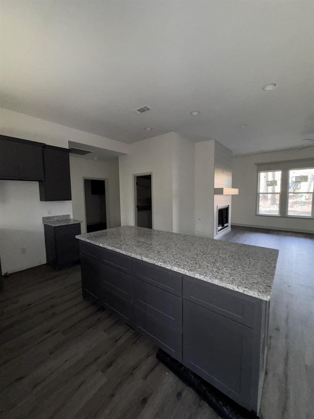 kitchen with open floor plan, visible vents, a kitchen island, and dark wood finished floors