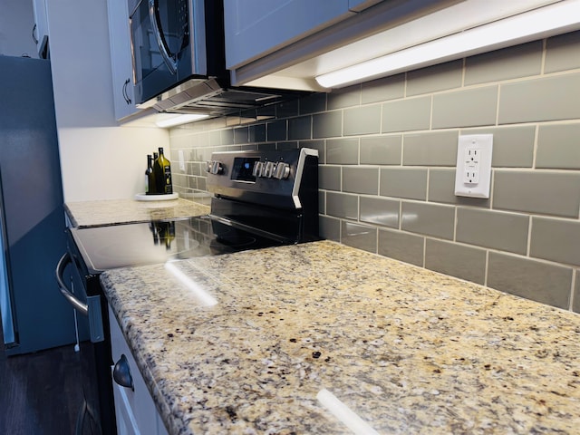 kitchen with electric range oven, decorative backsplash, fridge, light stone counters, and blue cabinetry