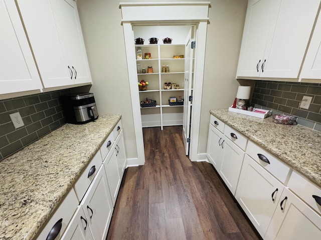 kitchen featuring white cabinetry, light stone countertops, backsplash, and dark hardwood / wood-style flooring