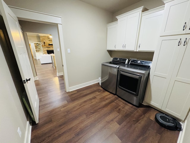 clothes washing area with dark wood-type flooring, cabinets, and washing machine and clothes dryer