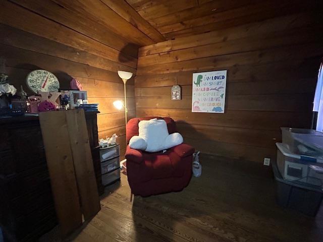 living area with wood-type flooring and wooden walls