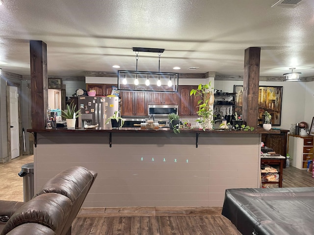 interior space featuring stainless steel appliances, a breakfast bar, pendant lighting, and light hardwood / wood-style floors