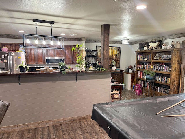 kitchen featuring billiards, a textured ceiling, appliances with stainless steel finishes, pendant lighting, and hardwood / wood-style floors