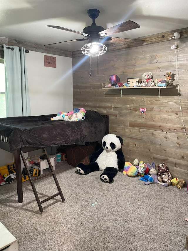 unfurnished bedroom featuring carpet flooring, ceiling fan, and wood walls