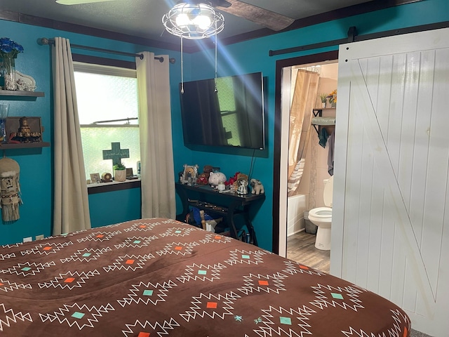 bedroom with hardwood / wood-style flooring, a barn door, and connected bathroom