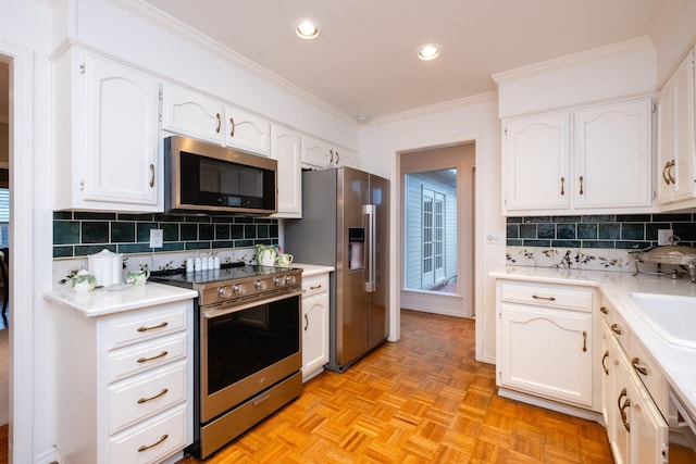 kitchen featuring light parquet flooring, appliances with stainless steel finishes, and white cabinets