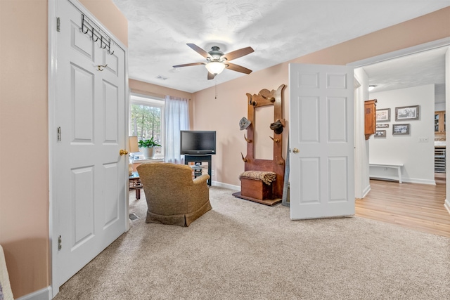 living area featuring ceiling fan and carpet