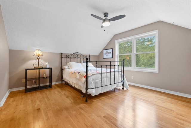 bedroom featuring lofted ceiling, hardwood / wood-style floors, a textured ceiling, and ceiling fan