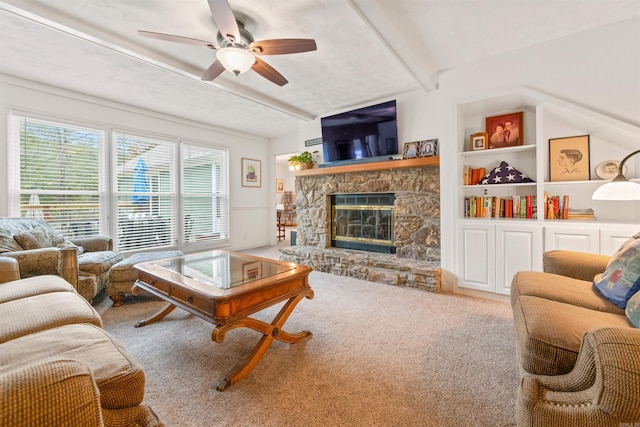 living room with built in shelves, beam ceiling, ceiling fan, a fireplace, and carpet