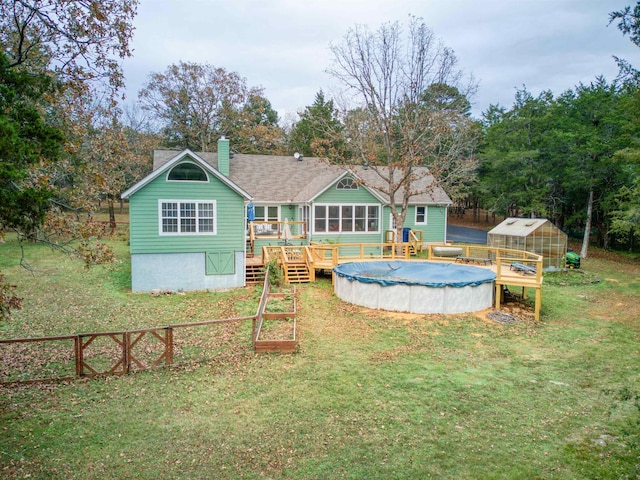 back of property featuring a yard, an outdoor structure, and a swimming pool side deck