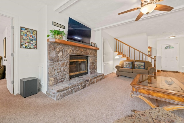 living room featuring a stone fireplace, lofted ceiling with beams, ceiling fan, and carpet flooring