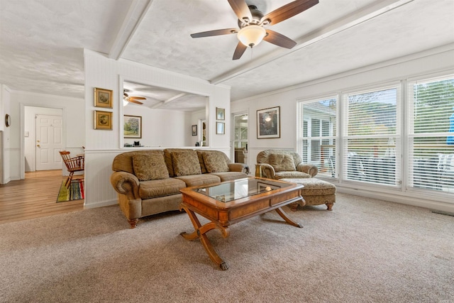 living room featuring beamed ceiling, ceiling fan, and carpet