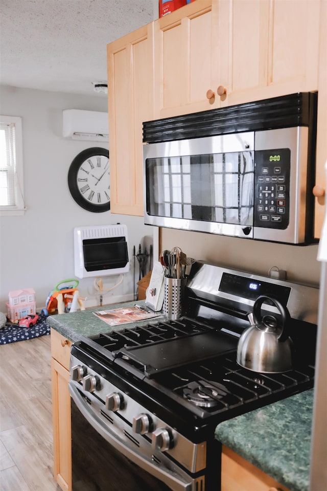 kitchen featuring a wall mounted air conditioner, a textured ceiling, light brown cabinets, appliances with stainless steel finishes, and light hardwood / wood-style floors