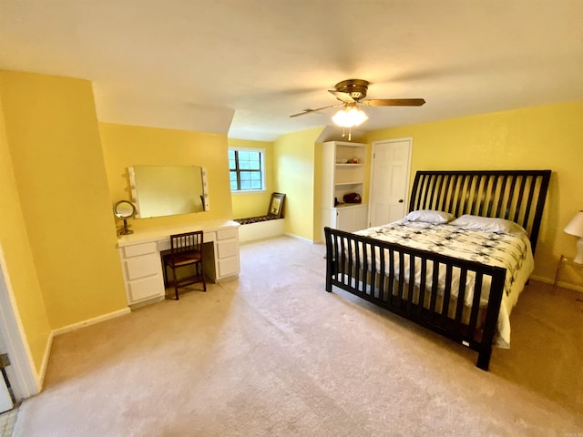 carpeted bedroom featuring built in desk and ceiling fan