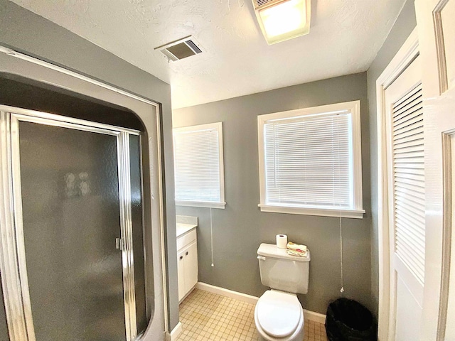 bathroom featuring vanity, toilet, a shower with shower door, and a textured ceiling