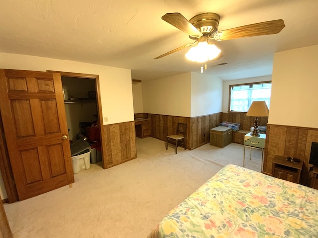 carpeted bedroom featuring ceiling fan and wooden walls