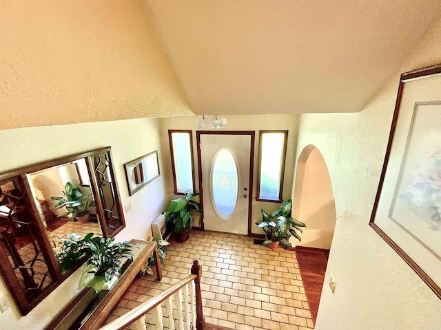 foyer with tile patterned flooring and vaulted ceiling