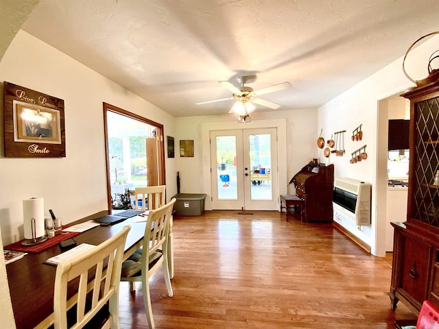 dining space with heating unit, light hardwood / wood-style flooring, french doors, and ceiling fan