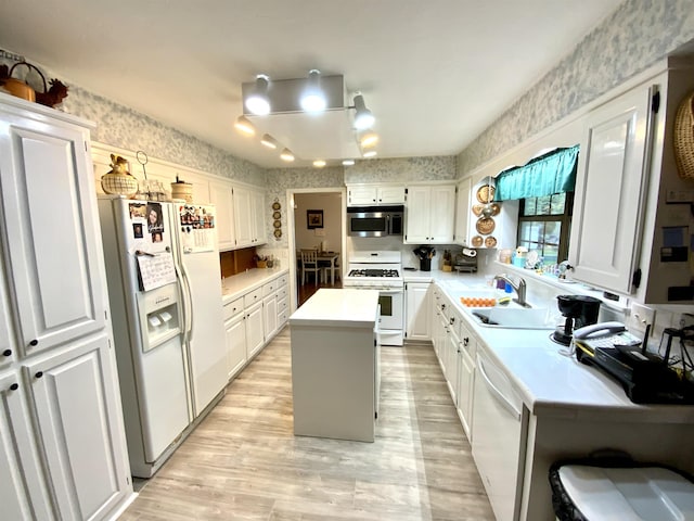 kitchen with sink, white appliances, light hardwood / wood-style floors, white cabinets, and a kitchen island