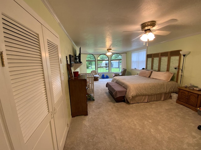 carpeted bedroom with ornamental molding and ceiling fan