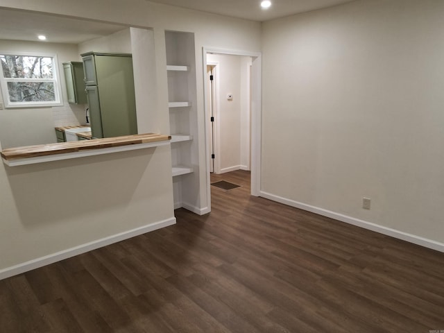 spare room featuring dark wood-type flooring and built in shelves