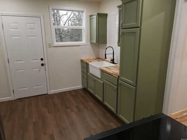 interior space featuring sink, butcher block counters, backsplash, green cabinetry, and dark hardwood / wood-style flooring