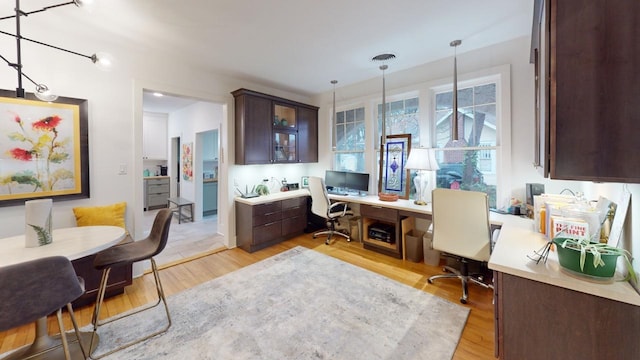 home office with built in desk and light hardwood / wood-style floors