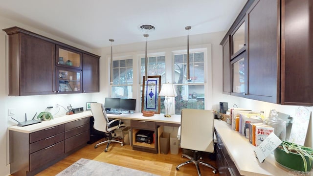 home office with built in desk and light hardwood / wood-style floors