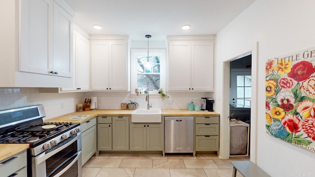 kitchen featuring sink, wooden counters, appliances with stainless steel finishes, white cabinets, and decorative light fixtures