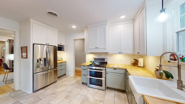 kitchen featuring sink, white cabinetry, decorative light fixtures, gray cabinets, and stainless steel appliances