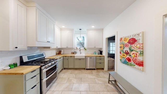 kitchen with butcher block counters, sink, pendant lighting, stainless steel appliances, and backsplash