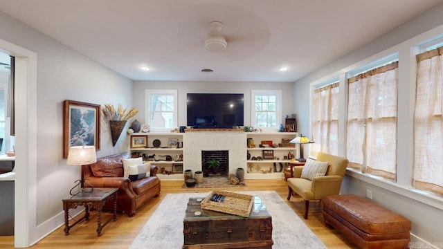 living room with a fireplace, light hardwood / wood-style flooring, and ceiling fan