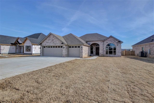 french country home featuring cooling unit, a garage, and a front yard