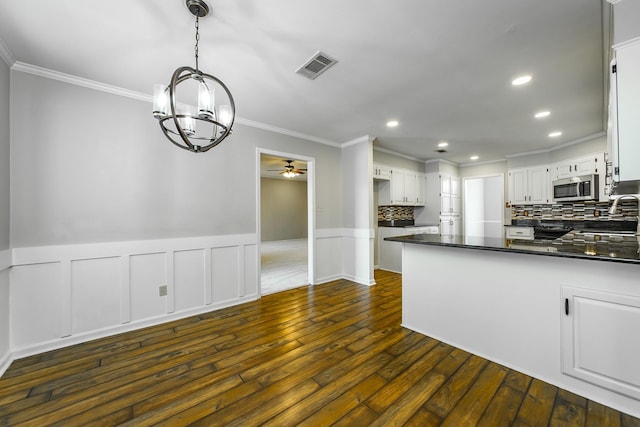 kitchen featuring pendant lighting, tasteful backsplash, white cabinetry, crown molding, and dark wood-type flooring