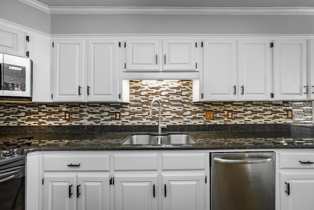 kitchen with sink, ornamental molding, appliances with stainless steel finishes, dark stone counters, and white cabinets