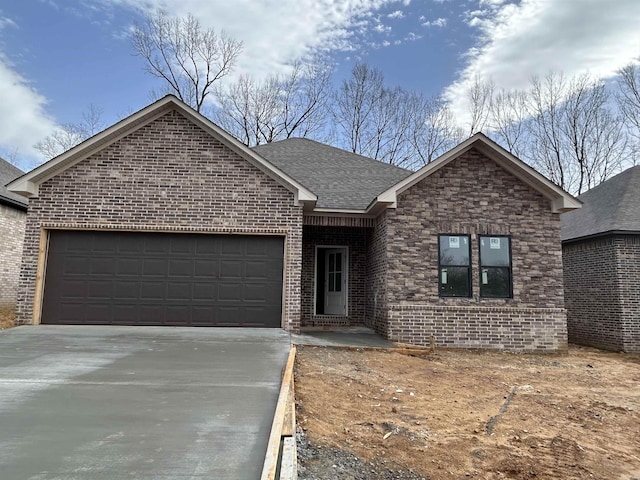 ranch-style house with brick siding, concrete driveway, a garage, and a shingled roof