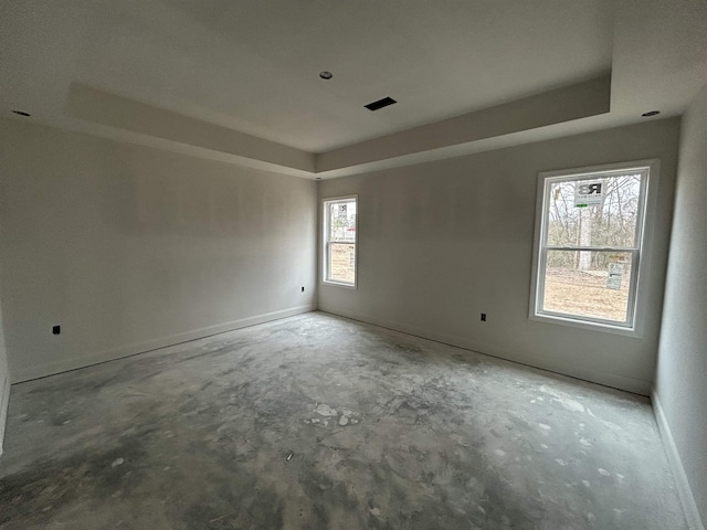 unfurnished room featuring a tray ceiling and concrete floors