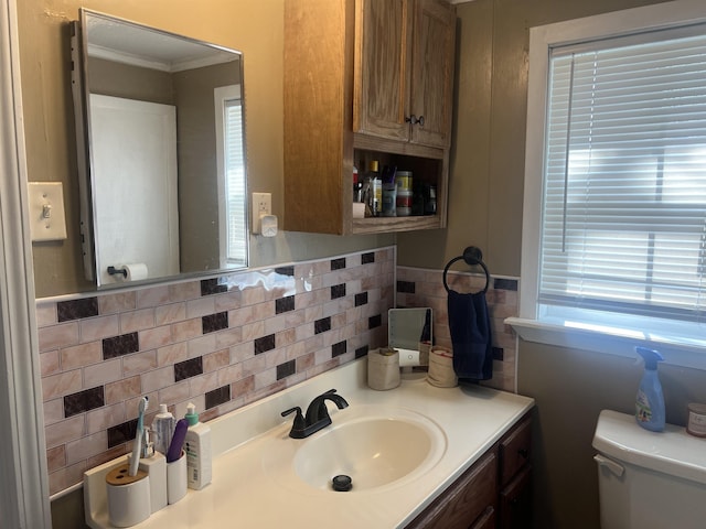 bathroom with crown molding, vanity, toilet, and decorative backsplash