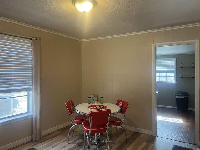 dining room with hardwood / wood-style flooring, ornamental molding, and a textured ceiling