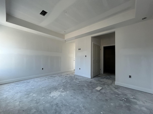 unfurnished room featuring a tray ceiling, baseboards, visible vents, and unfinished concrete floors