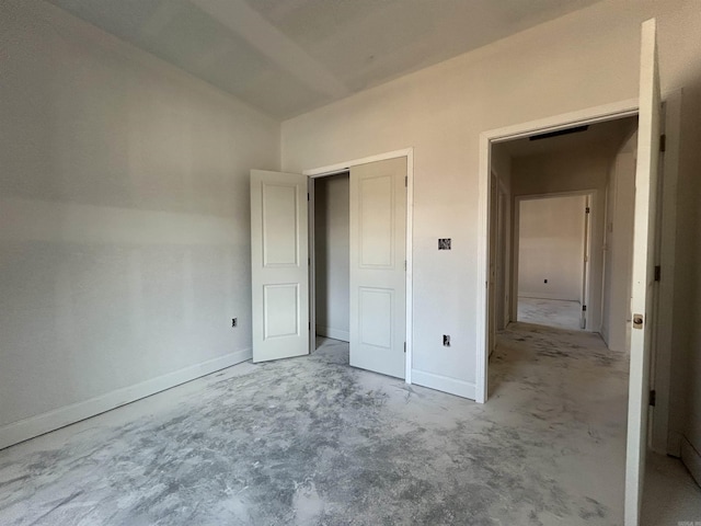 unfurnished bedroom with lofted ceiling, unfinished concrete flooring, and baseboards