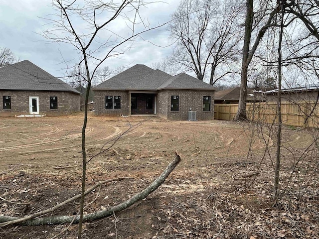 back of house with brick siding, cooling unit, roof with shingles, and fence