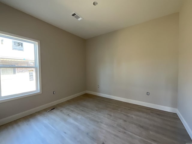 spare room featuring visible vents, baseboards, and wood finished floors