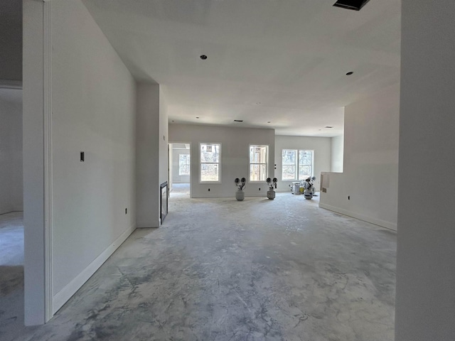 unfurnished living room featuring unfinished concrete floors and baseboards