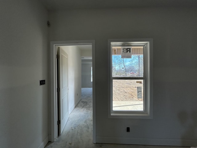 hall with concrete flooring and baseboards