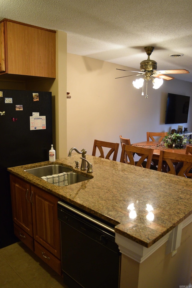 kitchen with sink, stone countertops, a textured ceiling, a kitchen breakfast bar, and black appliances