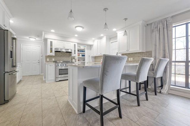 kitchen with high end appliances, ornamental molding, white cabinets, and decorative light fixtures