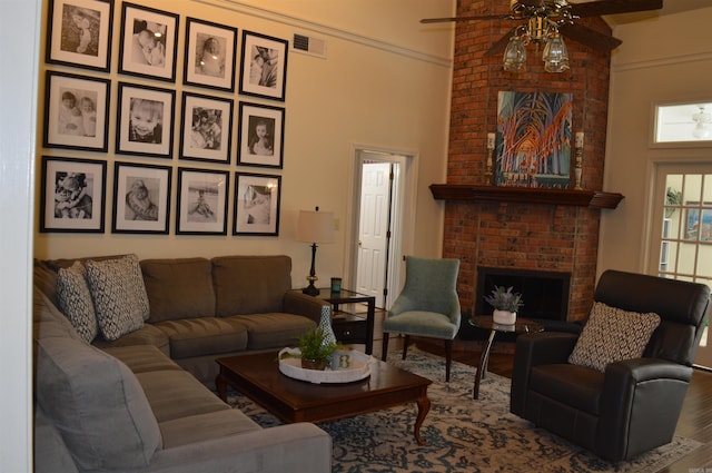 living room with crown molding, a brick fireplace, hardwood / wood-style floors, and ceiling fan